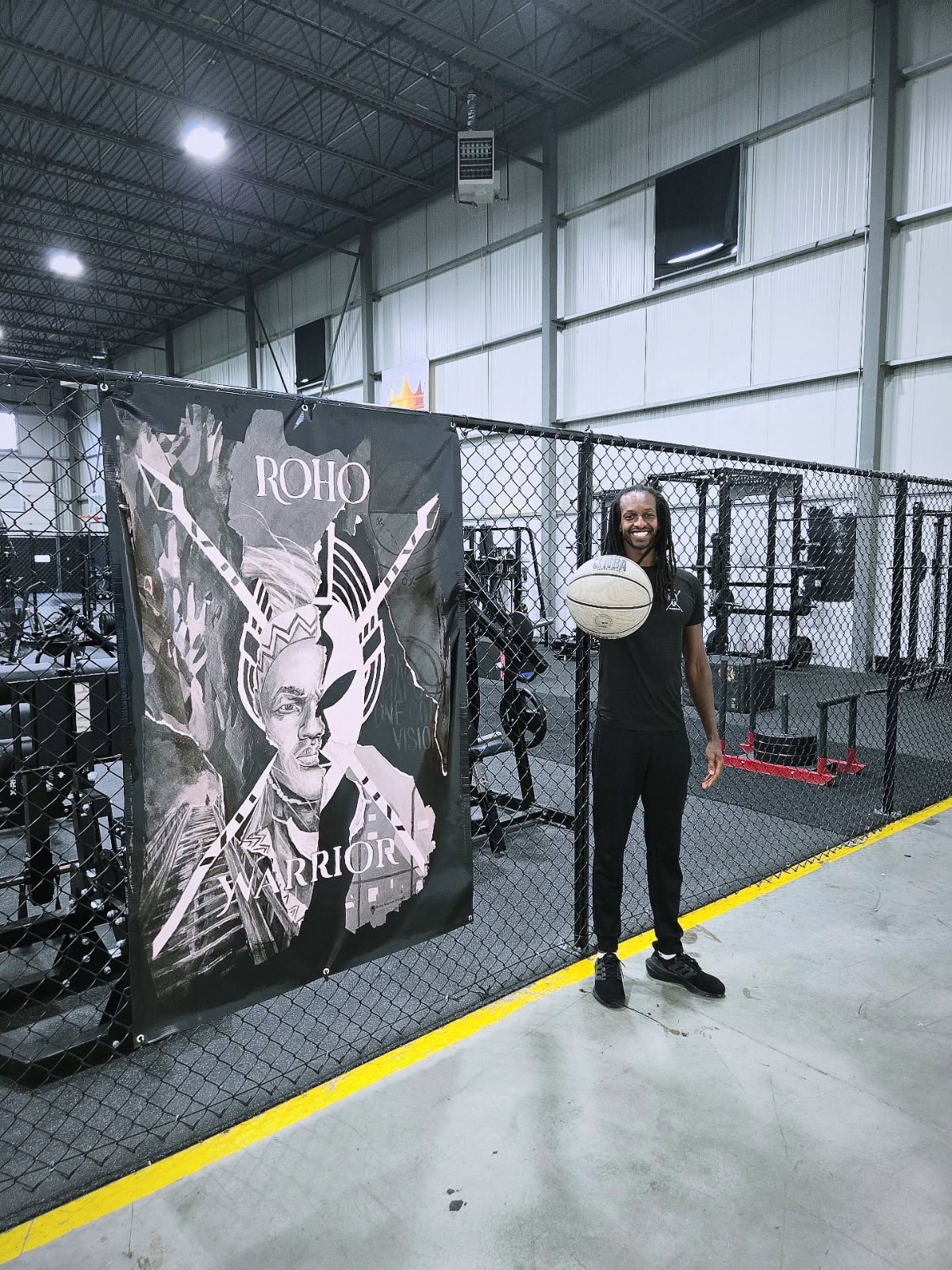 Coach with a basketball beside the ROHO Warrior banner