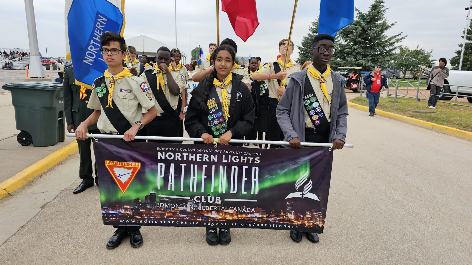 Northern Lights Pathfinder Club members in full uniform marching behind their club banner at a 2024 camporee