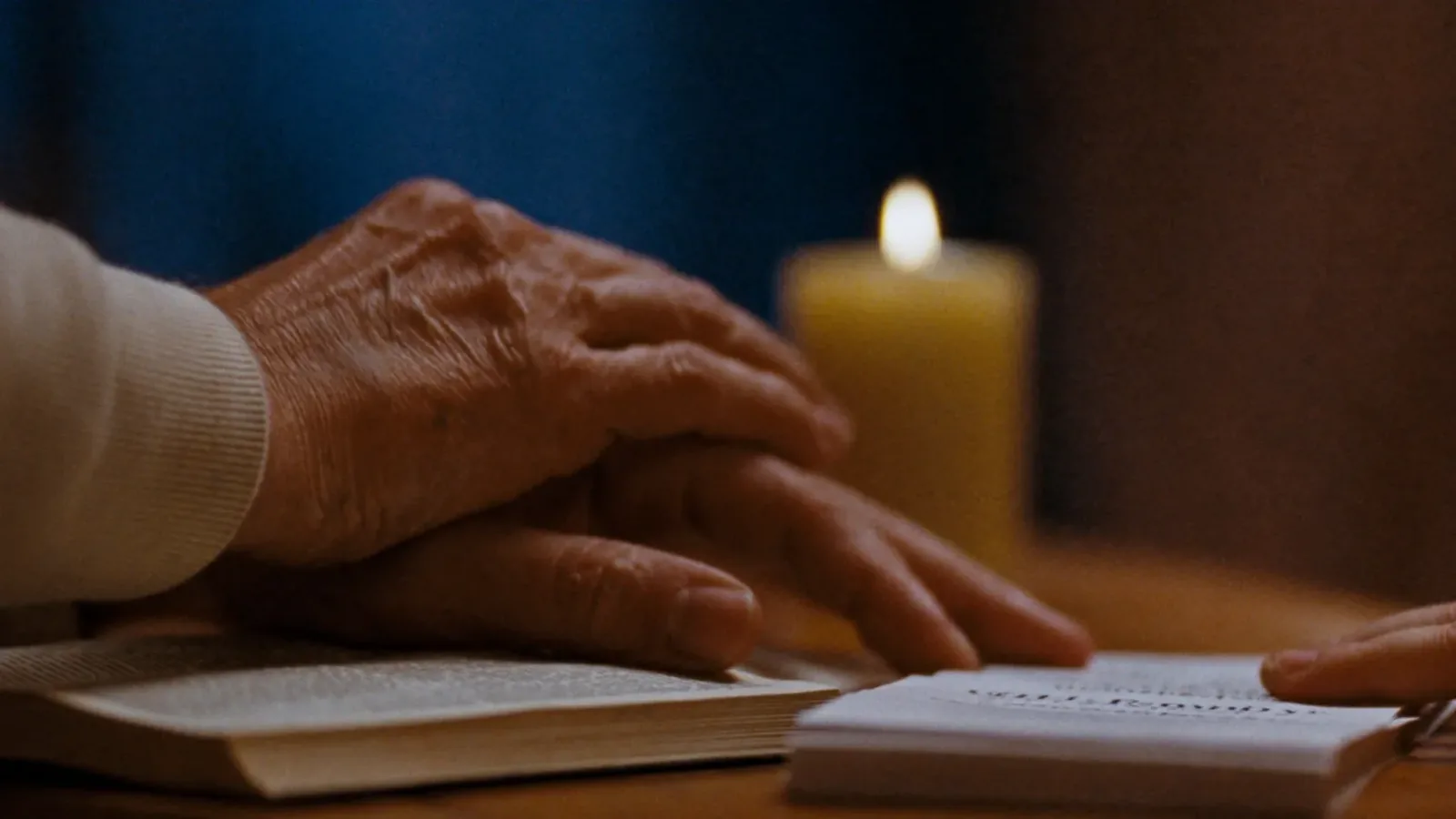 Hands resting on an open book beside a candle during a covenant ceremony