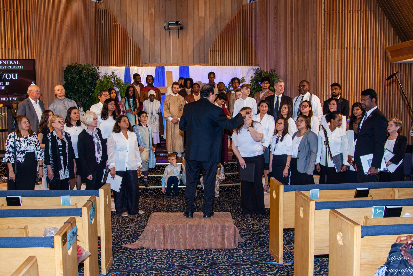 The music director conducting the Edmonton Central choir during the sung portion of a Sabbath service
