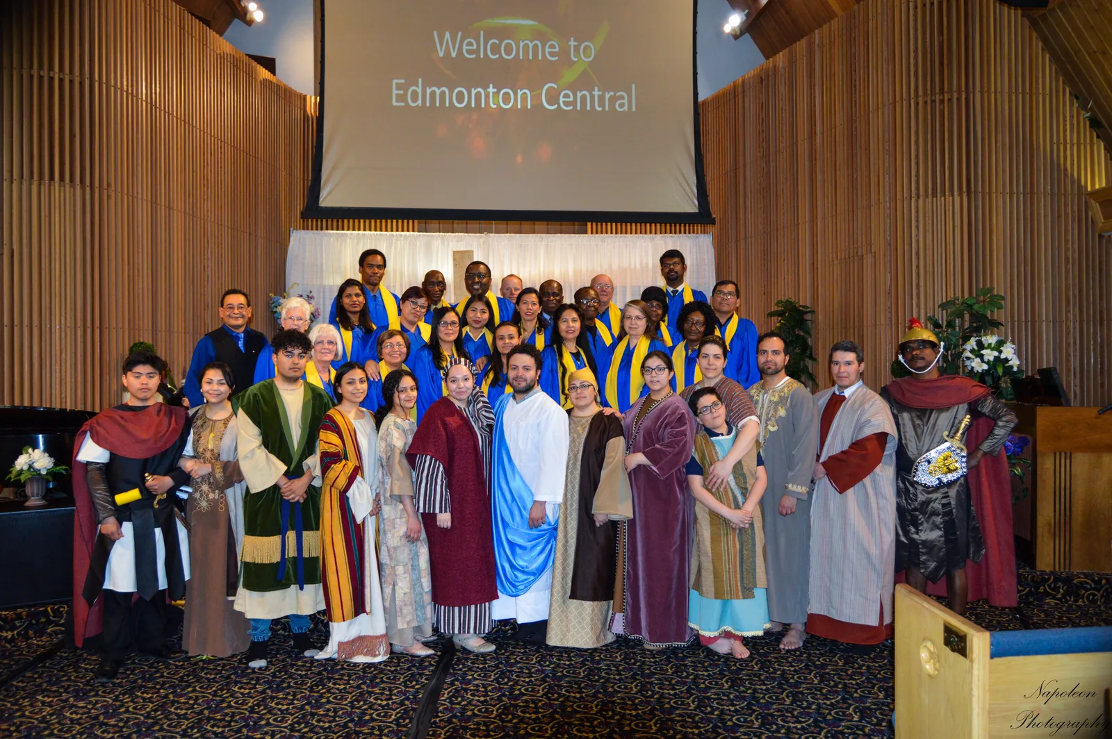 Choir members in blue and gold robes with the cast of the Easter programme in the Edmonton Central sanctuary