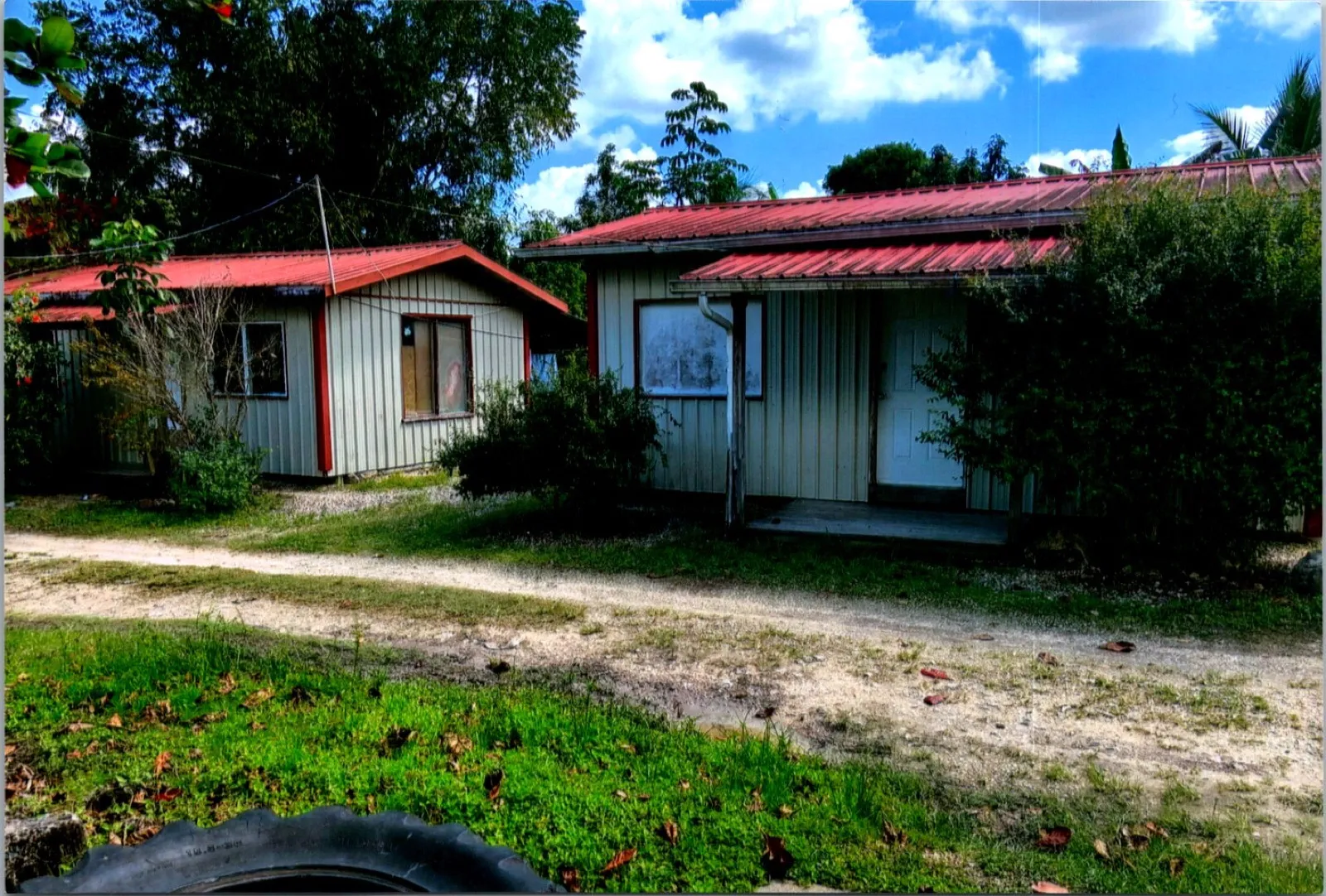 Two single-storey buildings with red metal roofs and white siding beside a gravel path