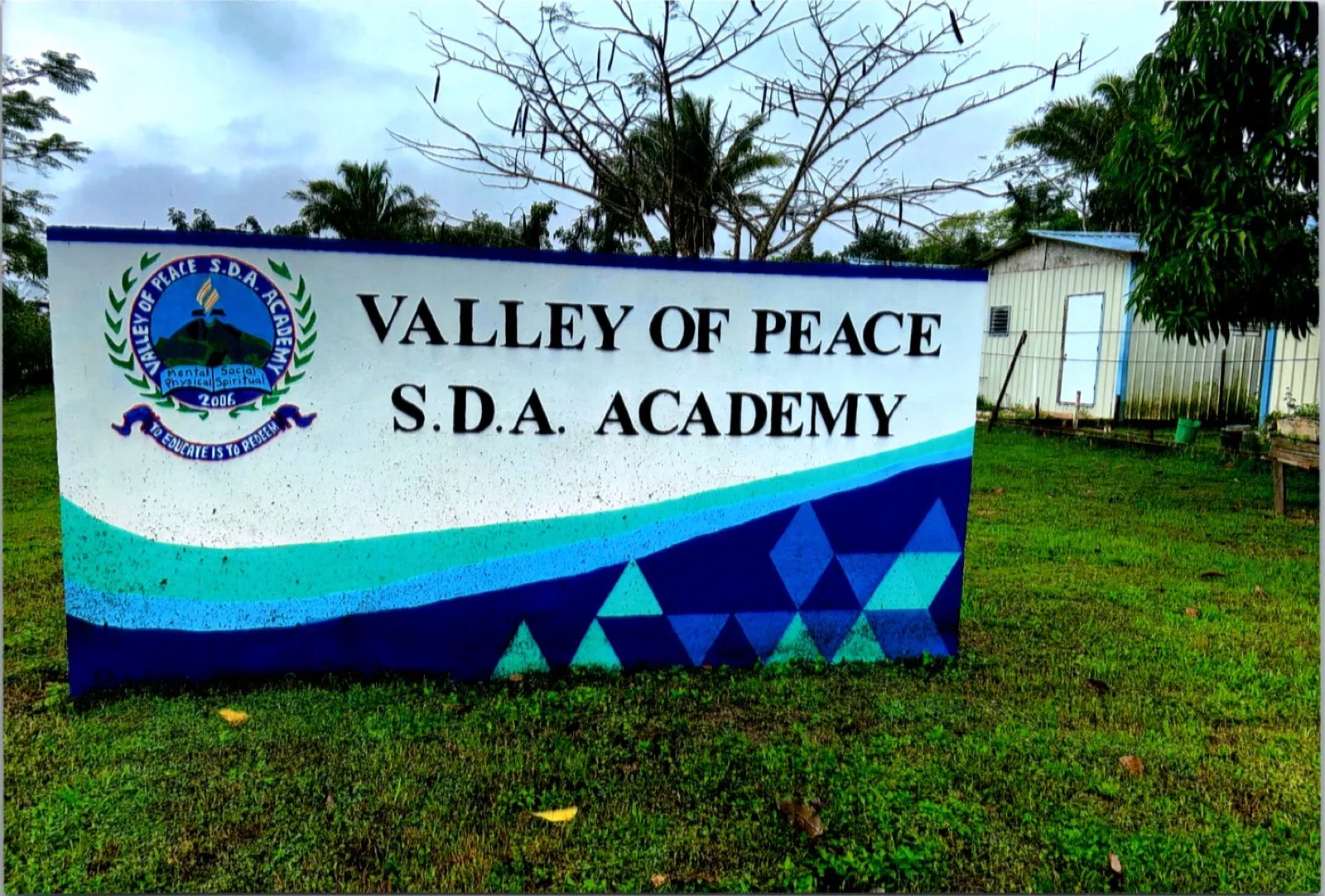 The painted sign of Valley of Peace S.D.A. Academy in Belize with the school crest